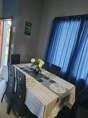 a dining room table with a vase of flowers on it at Le Grix Guesthouse in Nelspruit