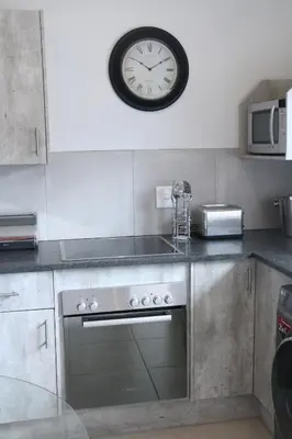 a clock on a wall above a stove in a kitchen at Millennium Body Guards Guesthouse in Hartbeespoort