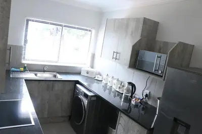 a kitchen with a sink and a washing machine at Millennium Body Guards Guesthouse in Hartbeespoort