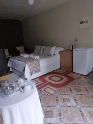 a bedroom with a bed and two tables in it at Hamba Kancane Ma-Africa Guest House in Graskop