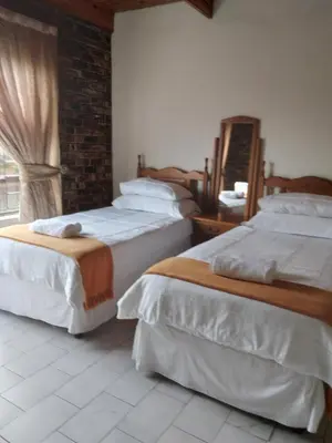 a bedroom with two beds and a mirror and a window at Hamba Kancane Ma-Africa Guest House in Graskop
