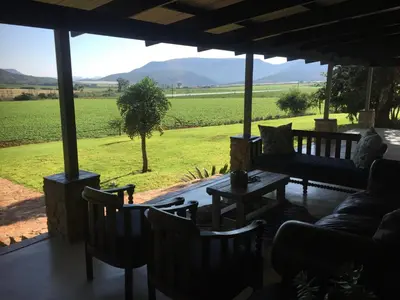 a porch with chairs and a table and a view of a field at Ploughman’s Rest in Ohrigstad