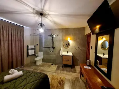 a bedroom with a bed and a bathroom with a sink at Diamantvallei Landgoed in Rayton