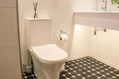 a white toilet in a bathroom with a black and white floor at Diamantvallei Landgoed in Rayton