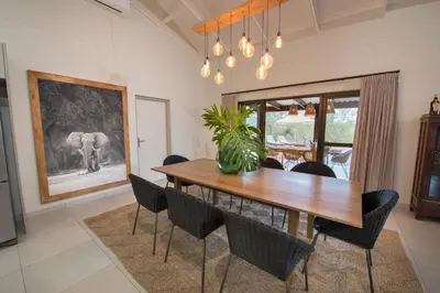 a dining room with a wooden table and chairs at Bushwillow Private Villa in Hoedspruit