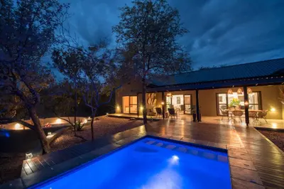 a swimming pool in front of a house at night at Bushwillow Private Villa in Hoedspruit