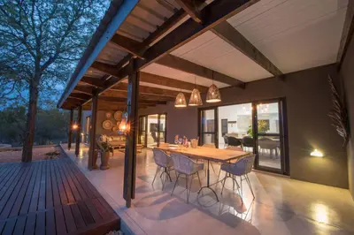 an outdoor patio with a wooden table and chairs at Bushwillow Private Villa in Hoedspruit