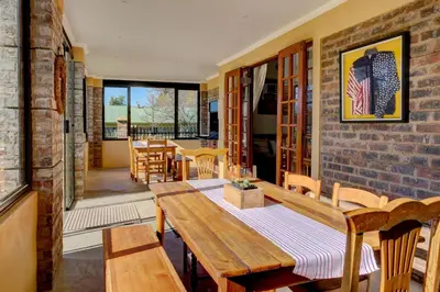 a dining room with a table and a brick wall at Mrs Simpson in Dullstroom