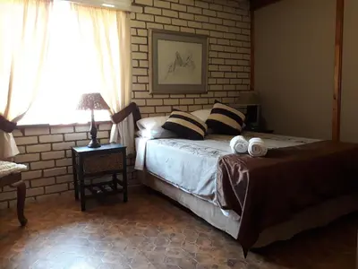 a bedroom with a bed and a brick wall at Die Plasie Two-Bedroom Flat in Hartbeespoort