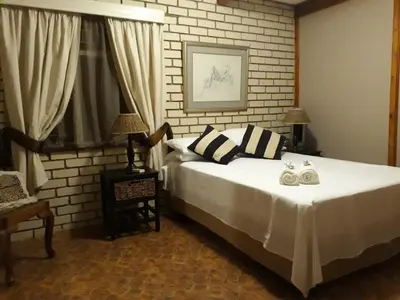a bedroom with a bed and a brick wall at Die Plasie Two-Bedroom Flat in Hartbeespoort