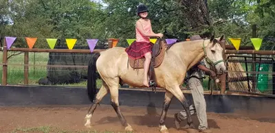 a young girl riding on the back of a horse at Die Plasie Two-Bedroom Flat in Hartbeespoort