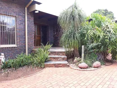 a brick house with a walkway in front of it at Die Plasie Two-Bedroom Flat in Hartbeespoort