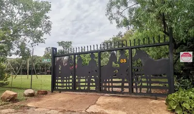 a black gate with a sign on it at Die Plasie Two-Bedroom Flat in Hartbeespoort