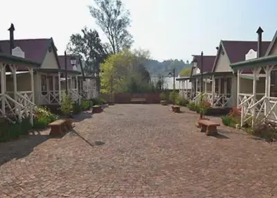 a group of houses with benches in a courtyard at The Pennefather in Haenertsburg