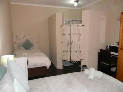 a bedroom with two beds and a desk with a computer at Ridderspoor Guesthouse in Middelburg