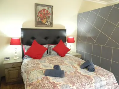 a bedroom with a large bed with red pillows at Ridderspoor Guesthouse in Middelburg