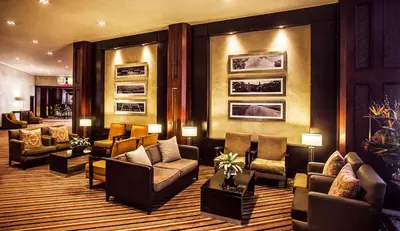 a lobby with couches and chairs and paintings on the wall at Southern Sun Pretoria in Pretoria