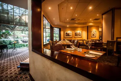 a restaurant with a bar with tables and chairs at Southern Sun Pretoria in Pretoria