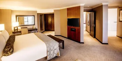 a hotel room with a bed and a flat screen tv at Southern Sun Pretoria in Pretoria