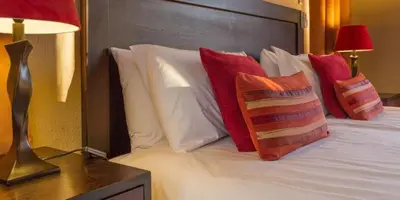 a bedroom with a bed with red and white pillows at Warthogs Rest in Hoedspruit