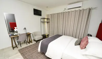 a bedroom with a white bed and a desk and a chair at Serurubele Boutique Hotel in Bushbuckridge