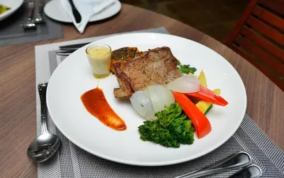 a plate of food with meat and vegetables on a table at Serurubele Boutique Hotel in Bushbuckridge