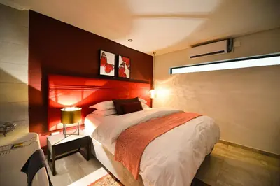 a bedroom with a large bed with a red headboard at Serurubele Boutique Hotel in Bushbuckridge