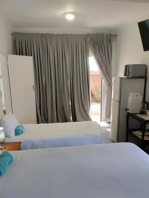 a bedroom with two beds and a window at Woodpecker Guesthouse Middelburg Mpumalanga in Middelburg