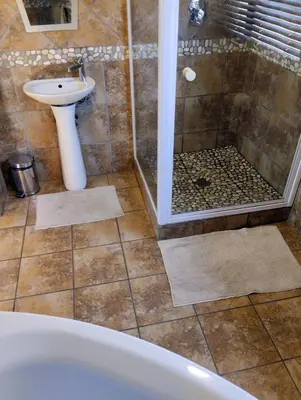 a bathroom with a tub and a sink and a shower at Woodpecker Guesthouse Middelburg Mpumalanga in Middelburg