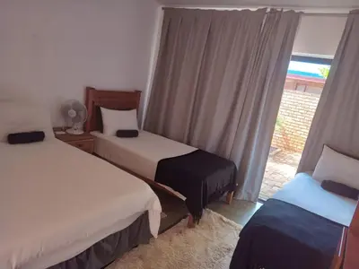 a hotel room with two beds and a window at Woodpecker Guesthouse Middelburg Mpumalanga in Middelburg