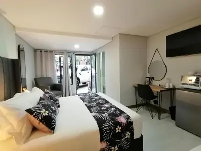 a bedroom with a large white bed and a desk at The Chameleon in Centurion