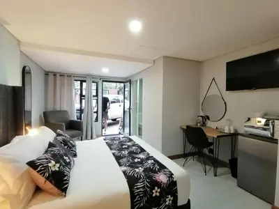 a bedroom with a bed and a desk and a television at The Chameleon in Centurion