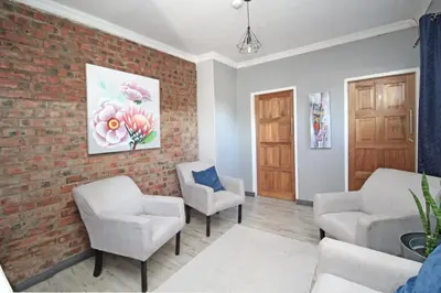 a waiting room with two chairs and a brick wall at The Chameleon in Centurion