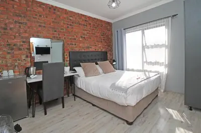 a bedroom with a bed and a brick wall at The Chameleon in Centurion