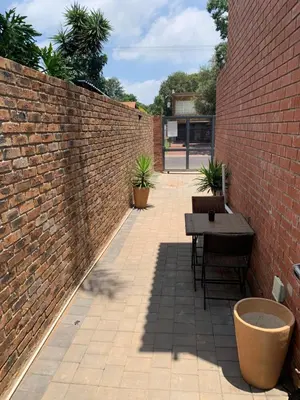 a brick wall with a table and chairs in a courtyard at The Chameleon in Centurion