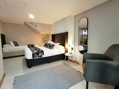 a bedroom with two beds and a chair and a mirror at The Chameleon in Centurion