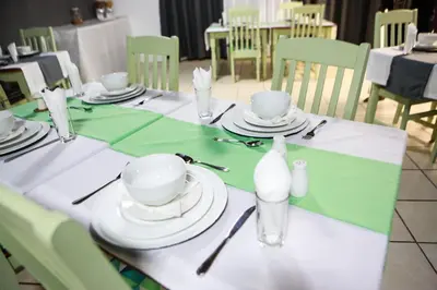 a green and white table with white plates and glasses at Gracious Lodge in Burgersfort