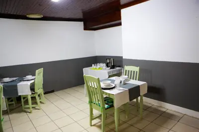 a dining room with two tables and chairs and a table with dishes on it at Gracious Lodge in Burgersfort