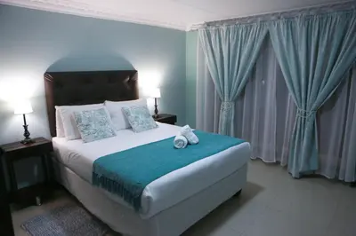 a bedroom with a large bed with blue walls and curtains at Gracious Lodge in Burgersfort