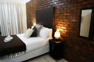a bedroom with a bed and a brick wall at Gracious Lodge in Burgersfort