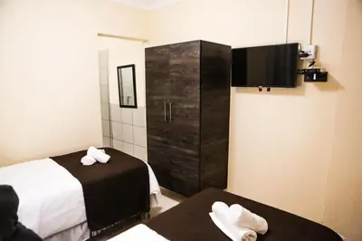 a hotel room with two beds and a television at Gracious Lodge in Burgersfort