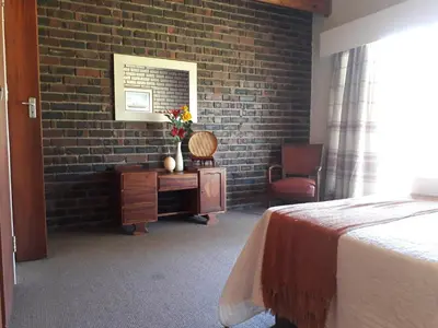 a bedroom with a bed and a brick wall at Die Plasie on-suite rooms in Hartbeespoort