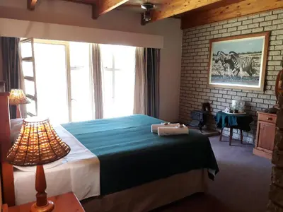 a bedroom with a bed and a large window at Die Plasie on-suite rooms in Hartbeespoort