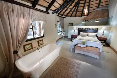 a bedroom with a large bed and a bath tub at Malilule Safaris in Hoedspruit