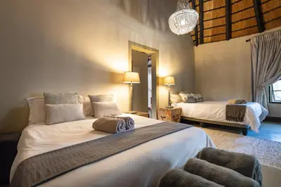 a bedroom with two beds and a chandelier at Malilule Safaris in Hoedspruit