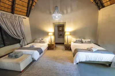 a bedroom with two beds and a chandelier at Malilule Safaris in Hoedspruit