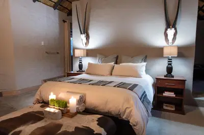 a bedroom with a large bed with two lights on it at Malilule Safaris in Hoedspruit