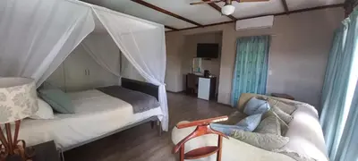 a bedroom with a bed and a couch at Kruger's Guest House in White River