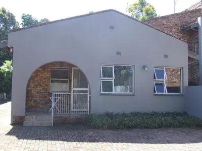 a white house with an arched door and windows at Kruger's Guest House in White River