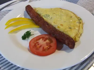 a plate of breakfast food with a sausage and a tomato at Kruger's Guest House in White River